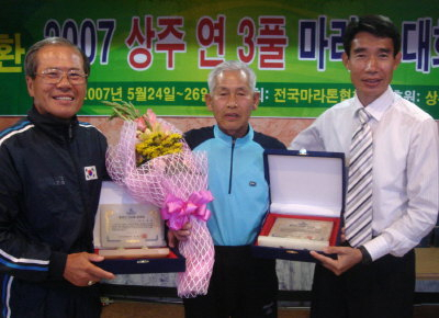 ▲ 연 3풀 상주대회에서 200회 완주기록을 달성한 석병환(중앙) 씨와 100회를 완주한 이영정 씨가 마라톤협회 장영기(오른쪽) 회장으로부터 완주패를 받고 기뻐하고 있다.