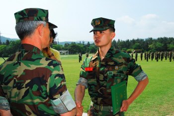 ▲ 이홍희(왼쪽) 해병대 제1사단장이 1000기 대표 안병욱 예비역 병장에게 전역증을 수여하고 있다.
