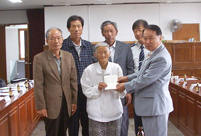 지난 10일 자양면 이장협의회에서 이진옥 씨에게 1천216만 원이 든 통장을 건네주고 있다.