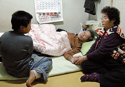 ▲ 경북 성주의 한 시골 마을에서 병든 조부모의 보살핌을 받고 있는 삼남매의 막내 동민이가 할아버지의 다리를 주무르고 있다. 정현미기자