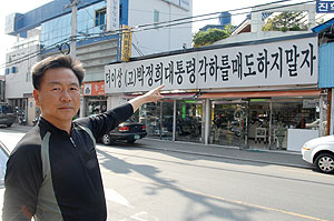 ▲ 4년째 내걸었던 이색 대형간판을 내리기가 못내 아쉬운 듯 간판을 가리키고 있는 여동활씨.