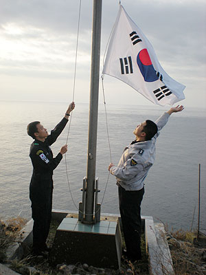 ▲ 독도경비대 이현우(오른쪽) 부장과 대원이 동도 정상 태극기를 교체, 게양하고 있다.