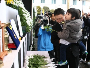 ▲ 고 이상기 경위의 아들 동욱군이 삼촌에게 안겨 아버지의 영정 앞에 헌화하고 있다.