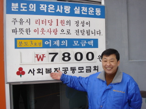 ▲ 분도석유 김현철 대표가 3호점에서 전날 모금한 액수를 가리키며 웃고 있다. 모현철기자