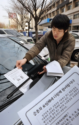 ▲ 승용차 선택요일제 참여율을 높이기 위해 공무원이 구청에 주차된 요일제 미참여 차량에 안내문을 배부하고 있다. 김태형기자 thkim21@msnet.co.kr