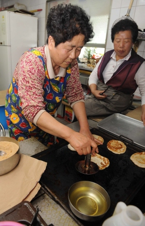 ▲ 호떡 할매 이신자(왼쪽)씨가 지난 19일 한국갱생보호공단 대구지부를 찾아 갱생 대상자들에게 나눠줄 사랑의 호떡을 굽고 있다. 정운철기자 woon@msnet.co.kr