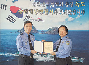 ▲동해해양경찰서 조준억 서장이 정광태씨를 독도경비함 일일 명예함장으로 위촉하고 있다.