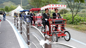 신현국 문경시장과 고오환 문경시의회의장이 나란히 사륜 자전거를 타고 새재 자전거길을 달리고 있다.