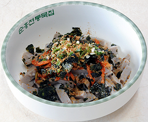 흰 사발에 소담스럽게 담아낸 순흥묵밥. 푸짐하게 채쳐 놓은 묵에다 멸치육수를 붓고 무생채와 김치를 채썰어 고명으로 얹고 김 가루와 깨소금을 뿌렸다.
