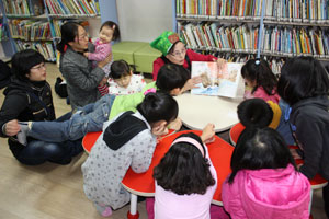 동부도서관의 이야기꾼 할머니가 방학을 맞은 초등학생들과 영유아들에게 그림책을 읽어주고 있다.