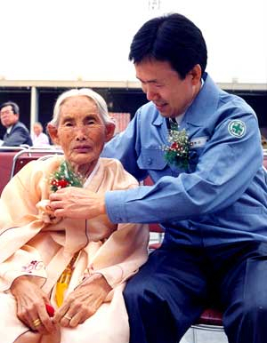 한삼화 회장이 1994년 10월 삼한C1 예천 공장 준공식에서 어머니 전해금 여사에게 꽃을 달아주고 있다.
