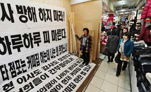 커피숍 개점을 둘러싸고 상가번영회와 갈등을 빚고 있는 J씨가 플래카드를 내 걸고 시위를 하고 있다. 성일권기자 sungig@msnet.co.kr