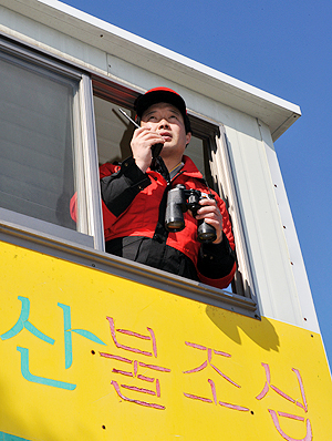 산불 감시에는 무전기와 망원경이 필수. 무전기는 현장 상황을 수시로 구청 상황실과 산 아래 초소에 알려야 하고, 망원경은 정밀한 감시를 위한 필수품이다.