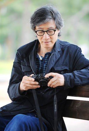구본창 교수가 사진학과 건물 앞 야외 휴게실에서 자신의 카메라를 들여다보고 있다.
