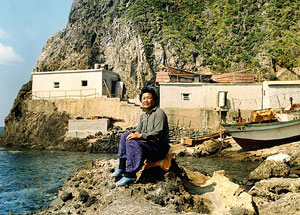 독도 서도 선가장 앞 바위에서 숙소를 배경으로 기념 촬영한 제주 해녀 고순자씨. 현재 제주시에 살고 있다. 제주해녀박물관 제공