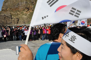 지난달 30일 일본의 중학교 사회과 교과서 검정 이후 독도를 찾는 방문객이 부쩍 늘었다. 독도 접안장에서 태극기를 흔들며 애국가를 부르는 관광객들.