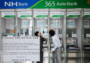 13일 오전 대구 시내 한 농협의 365코너에서 직원들이 금융 전산망 복귀를 기다리며 ATM기를 점검하고 있다. 왼쪽 출입문에 붙은 것은 서비스 장애 관련 사과문. 우태욱기자 woo@msnet.co.kr