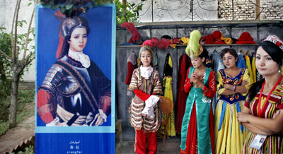 프랑스 구국의 영웅 잔다르크처럼 철갑옷을 입은 그림을 게시하고 기념촬영 영업을 하는 위구르 여성들.