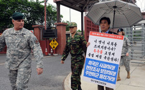 23일 오후 칠곡 왜관 캠프캐럴 미군기지 정문 앞에서 폭스 미8군기지관리사령관(왼쪽)이 대구경북 진보연대 백현국 상임대표의 고엽제 매립규탄 1인 시위를 쳐다보며 지나가고 있다. 김태형기자 thkim21@msnet.co.kr