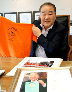 이재업 동성환경산업(주) 사장이 수학여행을 다녀온 학생들로부터 고마움의 표시로 받은 티셔츠와 사진 등을 보며 즐거워하고 있다. 엄재진기자
