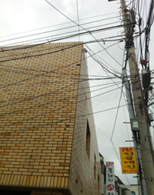 건물 벽에 바짝 붙은 전신주 때문에 비가 새는 외벽 방수공사조차 못하는 상황이다.