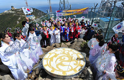 4343주년 개천절을 하루 앞둔 2일 팔공산 비로봉 정상 천제단에서 개천문화대축제 추진위원회 주최로 개천대제와 개천절 기념식이 열려 행사 관계자와 시민들이 삼족오 떡 자르기를 하면서 태극기를 흔들고 있다. 성일권기자 sungig@msnet.co.kr