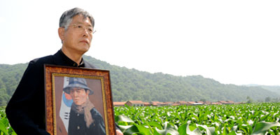 항일순국지사 추산 권기일 선생의 초상화를 안은 손자 권대용 씨가 옥수수가 무성한 신흥무관학교 옛터를 찾아 90여 년 전 이 옥수수밭에서 일본군과 싸우다 순국한 할아버지의 애국정신을 기리고 있다.