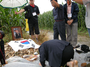 항일 독립지사 추산 권기일 선생의 손자 대용 씨가 8월 15일 광복절을 맞아 옥수수가 무성하게 자란 신흥무관학교 옛터 중국 길림성 통화시 광화진 합니하 강변 언덕을 찾아 추산 선생의 영정 앞에 태극기를 두고 비가 내리는 가운데 추모제를 올리고 있다.