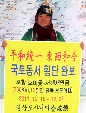 이달 16일 포항 호미곶을 출발해 12일 동안 새만금까지 360㎞의 한반도 동서횡단 걷기 여행을 마친 김찬진 경산시 전 주민생활지원국장이 27일 새만금에 도착해 기념 촬영을 하고 있다.
