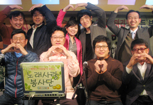 노래사랑봉사단체 단원들이 연습실이자 사무실을 겸하고 있는 막창가게에서 노래 연습 중 작은 하트모양의 제스처를 취했다. 앞줄 왼쪽에서 두 번째가 박동훈 단장.