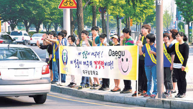 ▲9일 오전 대구남양학교 학생과 교사들이 수성구 두산오거리에서 출근길 운전자들에게 미소친절 캠페인을 벌이고 있다.