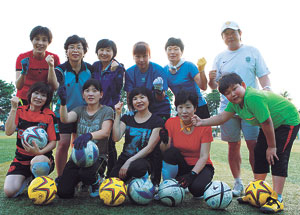 ▲울진의 아줌마축구단 회원들이 울진중 축구장에서 김도덕 코치와 명예회원 이주호 군과 함께 파이팅을 외치며 즐거워하고 있다.