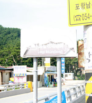 장기목장성 비각 위치를 안내하는 도로 표지판. 햇빛에 바래고 글자가 떨어져 나가 내용을 알아보기 힘들다
