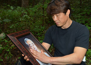 아버지 김명환 씨가 실종된 지 한 달 만에 시신을 찾은 김대경 씨가 발견 장소인 대구 동구 초례봉 아래 한 골짜기에서 영정사진을 들고 슬픔에 잠겨 있다. 성일권기자 sungig@msnet.co.kr