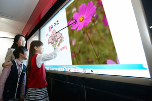 LG디스플레이 임직원과 어린이 모델들이 LCD 패널이 장착된 전자칠판으로 꽃 구조에 대한 교육을 시연해보고 있다. LG디스플레이 제공