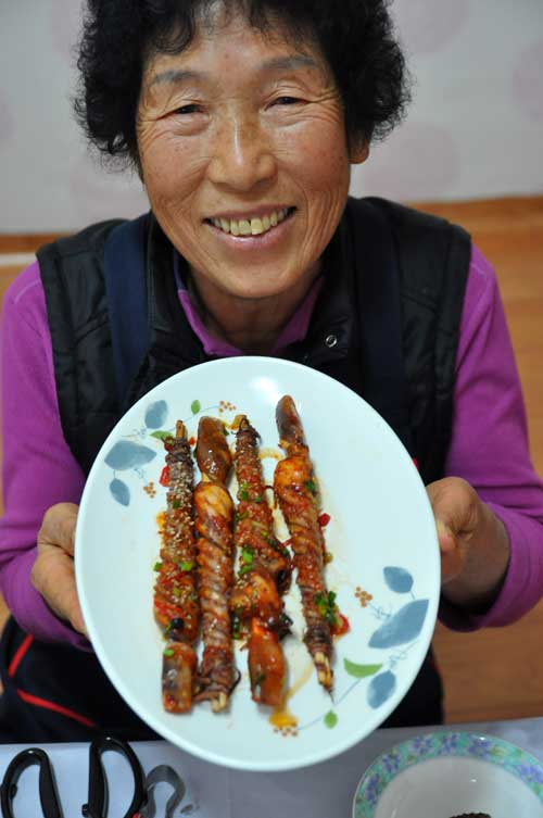 심희자 할머니가 세발낙지 호롱구이를 들고 신바람이 난 듯 재미나게 맛자랑을 하고 있다.