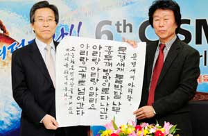 고윤환 문경시장과 이종선(오른쪽) 한국서학회 회장이 국립아리랑박물관 문경 유치를 위한 양해각서를 체결한 뒤 이 회장이 즉석에서 문경아리랑 가사를 붓으로 적은 문경한지를 들어 보이고 있다. 문경시 제공