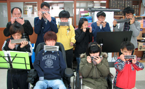 대구성보학교 전자조립실에서 하모니카 연습에 몰두하고 있는 맑은소리 하모니카 연주단원들. 뒷줄 맨 왼쪽이 노봉남 지도교사.