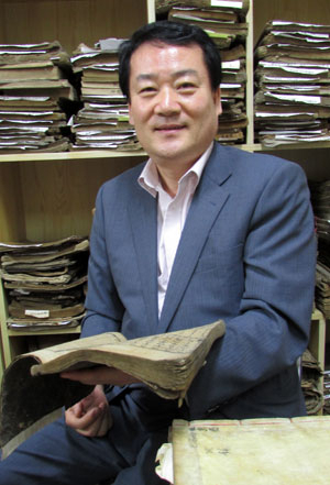경북대에 희귀고서 3천 권을 무상으로 기증한 박민철 씨가 자신이 운영하는 고서방에서 고서를 보면서 활짝 웃고 있다.