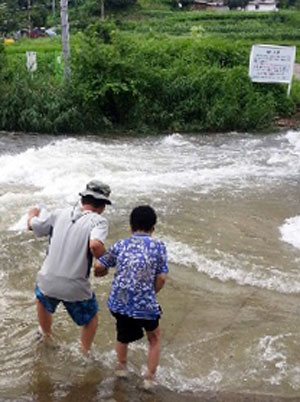 지난달 31일 전날 내린 비에 잠긴 문경 봉암사 입구의 다리를 주민들이 아슬아슬하게 건너고 있다. 고도현 기자
