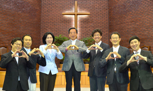 25년 동안 대구 내당교회 목회를 이끌고 있는 조석원 담임목사가 예배당에서 교회 당직자들과 함께 사랑과 나눔의 표시를 하고 있다.