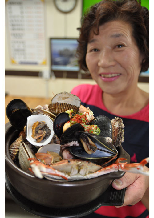 통영 멍게비빔밥 예찬론을 펼친 통영식도락 식당 대표 장미라 씨가 냄비에 가득 담은 통영 해물찜 그릇을 번쩍 들어 보이며 맛볼 것을 권하고 있다.