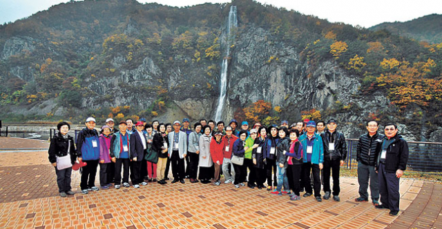 재부산 군위군향우회원들이 고로면 아미산 앞에서 기념사진을 촬영하고 있다. 군위군 제공