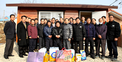 노모를 잃고 낡은 비닐하우스에서 살고 있는 A(45) 씨 쌍둥이 형제를 위해 상주 대림종합건설 직원들이 러브하우스를 마련한 후 기념촬영을 하고 있다. 사진 오른쪽은 쌍둥이 형제가 노모를 잃고 살았던 비닐하우스. 상주시 제공