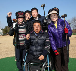 최경환(뒤쪽 가운데) 씨와 정승태(뒤편 왼쪽에서 두 번째) 씨가 포항 해도공원 파크골프장에서 경북장애인협회 포항시지회 이용선(휠체어 탄 사람) 회장 등 파크골프 동호회원들과 함께 파이팅을 외치고 있다.