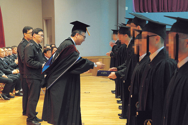 25일 포항교도소에서 열린 한국방송통신대 졸업식에서 졸업생들이 학위증을 받고 있다.