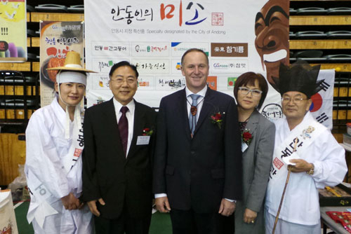 안동특산품해외홍보팀장 권용숙(왼쪽부터), 오클랜드 한인회회장 김성혁, 뉴질랜드 수상 존키, 국회의원 멜리사 리, 교민대표 김영오 씨가 행사장에서 안동 등 경북특산품 앞에서 활짝 웃고 있다.