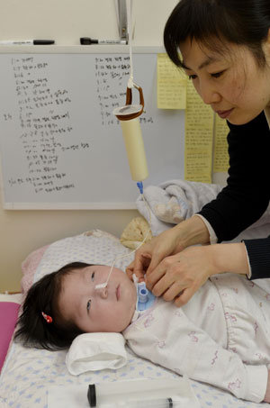 예진이가 주사기 용기에 담긴 분유를 코에 연결된 튜브를 통해 먹고 있다. 뒤쪽 칠판에는 예진이가 하루에 먹어야 할 약이 시간대별로 빼곡히 적혀 있다. 성일권 기자 sungig@msnet.co.kr