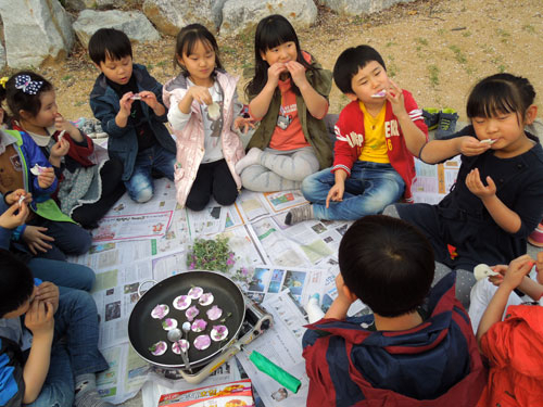 청송초등학교 학생들이 직접 구운 진달래 화전을 야외로 나와 먹으며 즐거워하고 있다. 청송교육지원청 제공