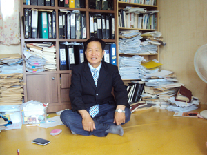 박주덕 씨가 스크랩북과 자료들을 모아 빼곡히 꽂아놓은 책장 앞에 앉아 있다. 박주덕 씨 제공